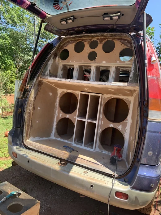Caja de MDF sin pintar armada dentro de la parte trasera de una van, con los huecos para cada parlante
